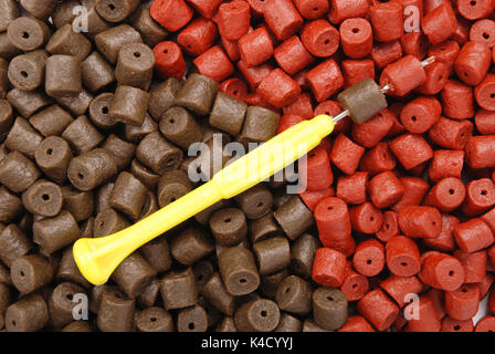 Gelbe Stinger Needle und braun mit roten vorgebohrte Heilbutt Pellets für Karpfen Angeln Hintergrund Stockfoto