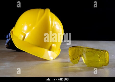 Gelben Helm, Schutzbrille und Arbeitshandschuhe für den Arbeiter, schwarzer Hintergrund Stockfoto