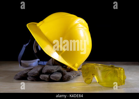 Gelben Helm, Schutzbrille und Arbeitshandschuhe für den Arbeiter, schwarzer Hintergrund Stockfoto