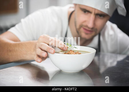 Close up Portrait von Chef dekorieren Suppe in der Küche Stockfoto