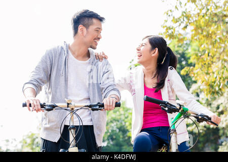 Jungen asiatischen Paar zusammen lachen, beim Reiten Fahrräder Stockfoto