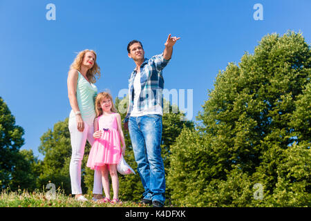 Junge Familie auf dem Feld, Vati, der auf etwas Stockfoto