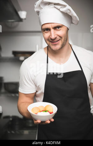 Portrait von zuversichtlich männlichen Chef hält Schüssel mit Dessert Stockfoto