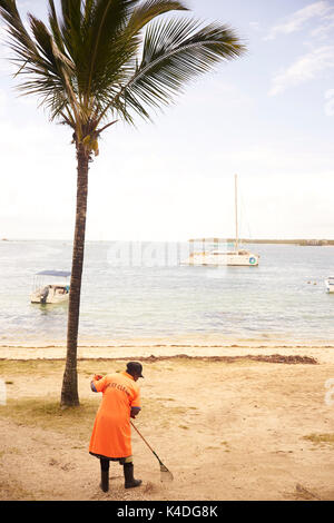 Frau auf Mauritius mit einer Harke Harken der Strand sauber Stockfoto