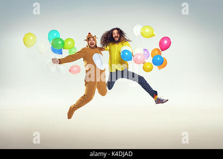 Bild präsentieren zwei lustige Männer springen und Holding Ballons Stockfoto