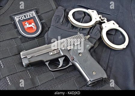Pistole mit Handschellen, Handschuhe auf blauen Uniform Shirt und taktische Weste mit Patch der Polizei Niedersachsen, Deutschland Stockfoto
