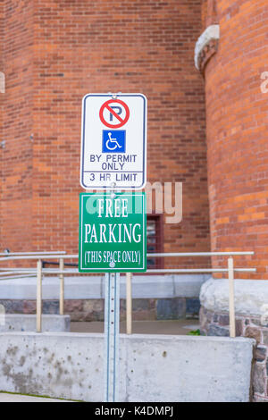 Zeichen, die eine Behinderte Parkplatz und eine andere, die angibt, dass es kostenlos zu parken. Stockfoto