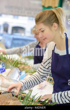 Junge Verkäuferin bietet frischen Fisch in einem Geschäft Stockfoto