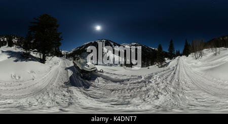 Schneemobil in einer mondhellen Nacht auf der Straße in den Bergen. Sphärische 360 180 Panorama. Stockfoto