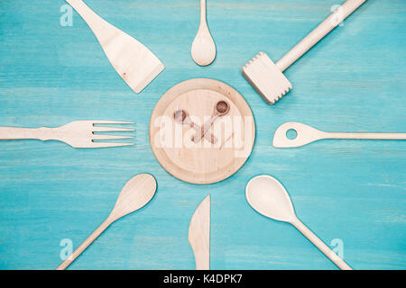 Blick von oben auf die verschiedenen Küchengeräte aus Holz mit Uhr Symbol auf Platte Stockfoto