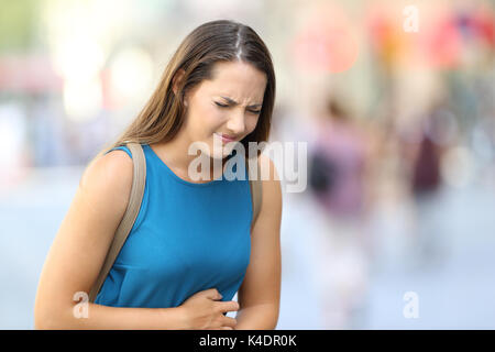 Single Frau mit Bauchschmerzen draußen auf der Straße Stockfoto