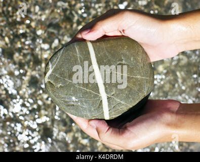 Große graue nasse See Stein in den Händen Stockfoto