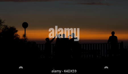 Sonnenuntergang Silhouette der Gruppe der Leute, die Fotos von sich selbst, mit Blick auf das Wasser am Plage L'Amelie, in der Nähe von Soulac-sur-Mer, Frankreich. Stockfoto