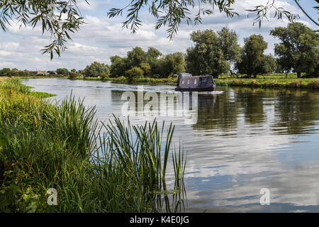 Einen blauen Kanal Boot nähert sich der Kathedrale von Ely in Cambridgeshire am Fluss Great Ouse. Stockfoto