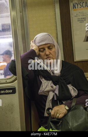 Müde Frau, einer U-Bahn zur Hauptverkehrszeit in Manhattan, New York City. Stockfoto