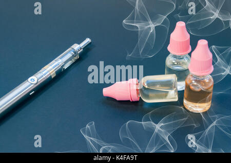 elfbar neue vape Eine elektronische Zigarette, eine vape und mehrere Flaschen Nachfüllen von  Flüssigkeiten für liegen auf einem dunklen Hintergrund Stockfotografie