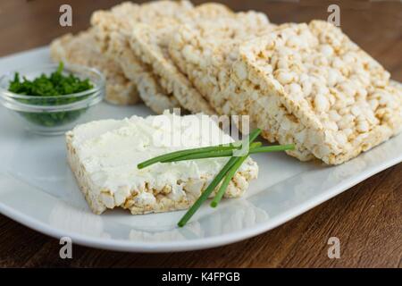 Reis Kuchen mit Frischkäse und Schnittlauch auf weiße Platte. Konzept der gesund, fettarm, Gewichtsreduzierung Diät Stockfoto