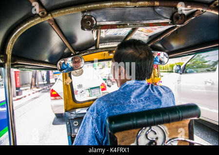 Eine glücklich lächelnde Tuk Tuk Fahrer in seinem Rückspiegel, Bangkok, Thailand gesehen. Stockfoto