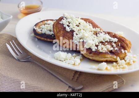 Hausgemachte glutenfreie Pfannkuchen mit Quark und Honig auf dem ovalen Schild serviert. Stockfoto