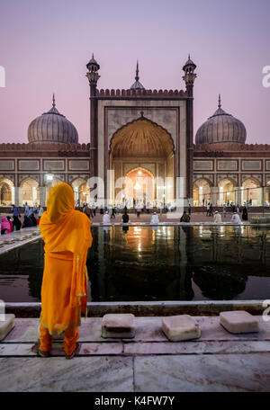 NEW DELHI, INDIEN - ca. Oktober 2016: Frau Beobachten der Jama Masjid Moschee in Alt Delhi in der Nacht. Aus rotem Sandstein und weißem Marmor gebaut Die Stockfoto