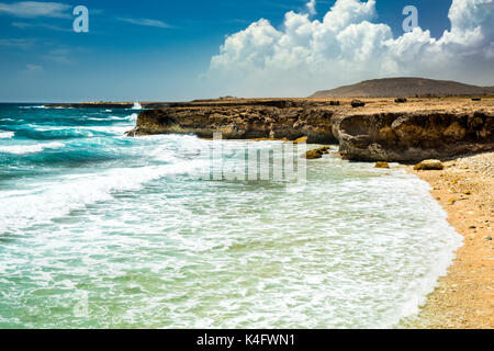 Sonnigen Sommertag mit blauem Himmel auf dem östlichen Ufer von Aruba. Schäumende Wellen splash den felsigen Strand. Stockfoto