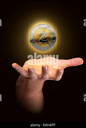 Eine männliche Hand beschwört eine schwimmende zcash cryptocurrency Hologramm in Gold und Silber physisch Münze Form auf einem dunklen Studio Hintergrund Stockfoto