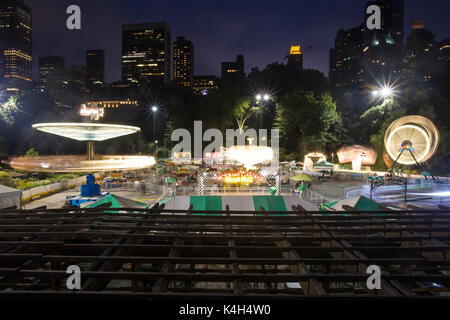 Vergnügungspark Lichter blur als Gäste eine warme Sommernacht an der Viktorianischen Gärten Vergnügungspark in New Yorks Central Park genießen. Stockfoto