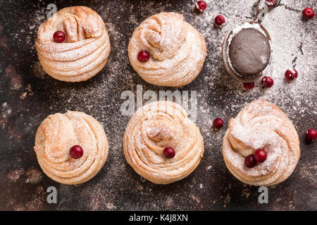 Delicious Cruffins kommen zusammen aus einem schuppigen Croissant in Form eines Muffins. Morgenbrötchen. Muffins auf dunklem Hintergrund. Stockfoto