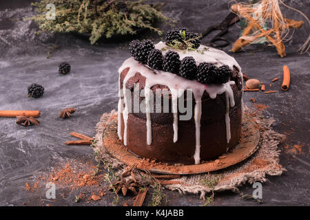 Unglaublicher Schokoladenkuchen. Dunkler und feuchter Schokoladen-Fudge-Kuchen. Kuchen mit Brombeeren und Zimt auf dunklem Hintergrund. Stockfoto