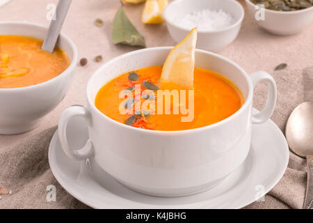 Vegane cremige Kürbissuppe, glutenfrei. Serviert mit Kürbiskernen und Zitrone für einen zusätzlichen Geschmack Kick. Stockfoto