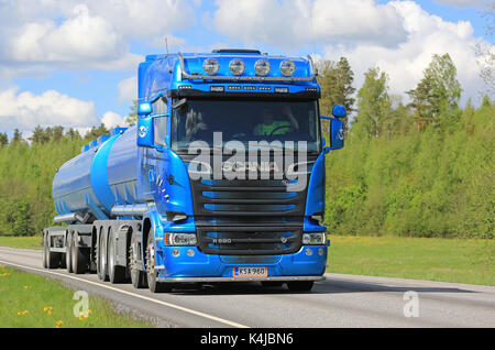 Salo, Finnland - 26. Mai 2017: blauer Scania 580 Tankwagen transportiert Waren entlang der Autobahn an der Frühling mit einem Hintergrund von grünem Laub und blauer Himmel mit Stockfoto