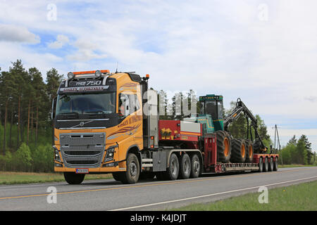 Salo, Finnland - 25. Mai 2017: gelb Volvo fh von kosken autokeskus Transporte logman811 h Wald Feldhäcksler auf Schwanenhals Anhänger auf der Autobahn auf einem Bea Stockfoto