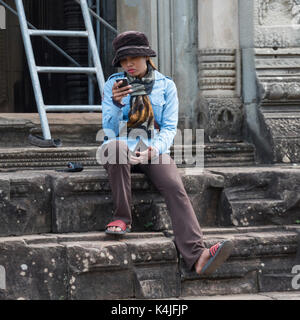 Frau an Ihr Handy auf Hindu Tempel in Angkor Wat, Banteay Samre, Siem Reap, Kambodscha Stockfoto