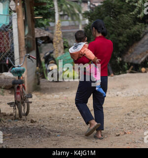 Ansicht der Rückseite Frau ihr Kind tragen, Luang Prabang, Laos Stockfoto