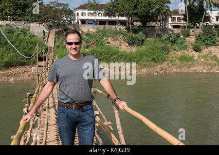 Mann stand auf Bambus Brücke, Fluss Nam Khan, Luang Prabang, Laos Stockfoto