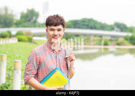 Hochschule asiatischen männliche Kursteilnehmer holding Buch über den Park Stockfoto