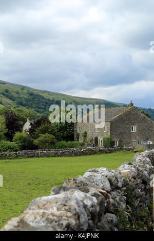 Traditionelle Bauernhaus aus Stein mit Feld- und Hawkswick Moor im Hintergrund von der mittleren Fahrspur in Kettlewell, Yorkshire Dales, North Yorkshire, England Stockfoto