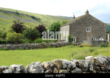 Traditionelle Bauernhaus aus Stein mit Feld- und Hawkswick Moor im Hintergrund von der mittleren Fahrspur in Kettlewell, Yorkshire Dales, North Yorkshire, England Stockfoto