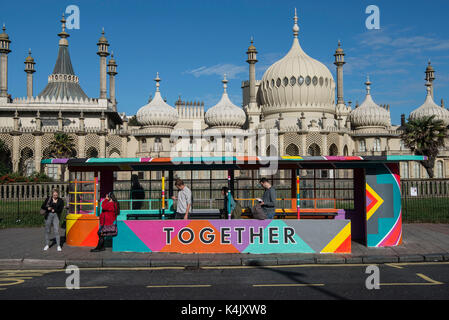 Die Menschen warten auf einen Bus im Art Deco Stil Bushaltestelle vor dem Royal Pavilion, Brighton, die meisten sind in ihre Mobiltelefone verfasst. Das Tierheim Stockfoto