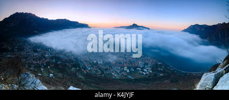 Panoramablick von Nebel bei Sonnenaufgang über der Stadt Lecco von Monte San Martino, Provinz von Lecco, Lombardei, Italien, Europa Stockfoto