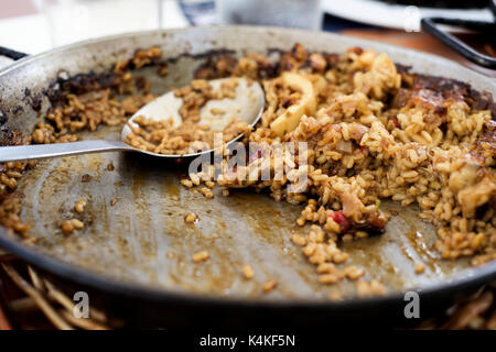 Nahaufnahme eines paellera, die Paella Pfanne, mit einige spanische Paella und ein Löffel, auf einem Tisch während der Mittagspause Stockfoto