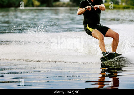 Männliche wakeboarder Fahrten auf See in Wakeboard Spritzwasser Stockfoto