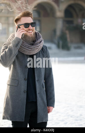 Lächelnd mann im winter Jacke, am Telefon zu sprechen und smmiling Stockfoto