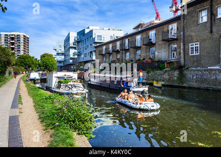 Eine Gruppe junger Männer und Frauen, die sich in einem Schlauchboot abkühlen, wenn die Temperaturen steigen, Regent's Canal, Islington, London, Großbritannien Stockfoto