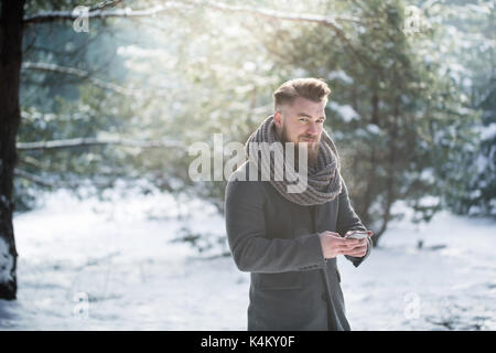 Attraktiver Mann sms eine Nachricht im verschneiten Wald Stockfoto