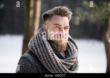Mann im Winter Kleidung auf Kamera und Stellung im weißen Holz Stockfoto