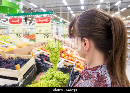 Samara, Russland - 3. September 2017: Junge Frau Auswahl von frischen Weintrauben bei Einkaufen im Supermarkt Stockfoto