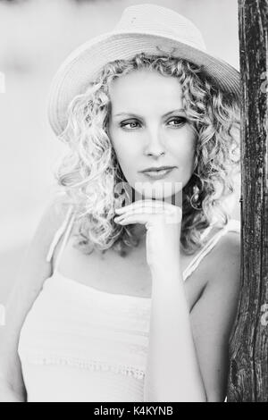 Nachdenklich, schöne Frau mit Hut und lockiges Haar Stockfoto