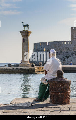 Fischer, bewundern Sie die Aussicht auf Mandraki Marina, Rhodos, Griechenland. Stockfoto