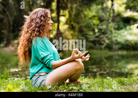 Schöne Mädchen übt Yoga am Morgen Wald. Stockfoto